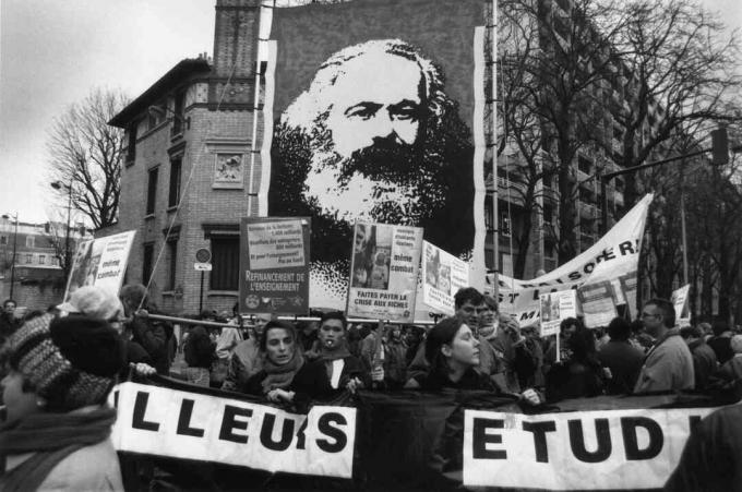 Französische Arbeiter streiken 1990 für bessere Löhne und tragen ein Banner mit einem Bild von Karl Marx, das die anhaltende Bedeutung seiner Ideen und seines Aktivismus zeigt. Erfahren Sie hier mehr über die marxistische Soziologie.